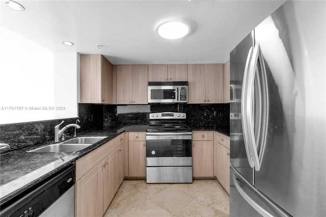 kitchen with light brown cabinets, sink, decorative backsplash, dark stone countertops, and stainless steel appliances