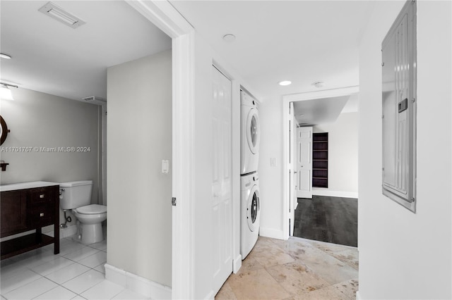 laundry area featuring stacked washing maching and dryer and light tile patterned floors