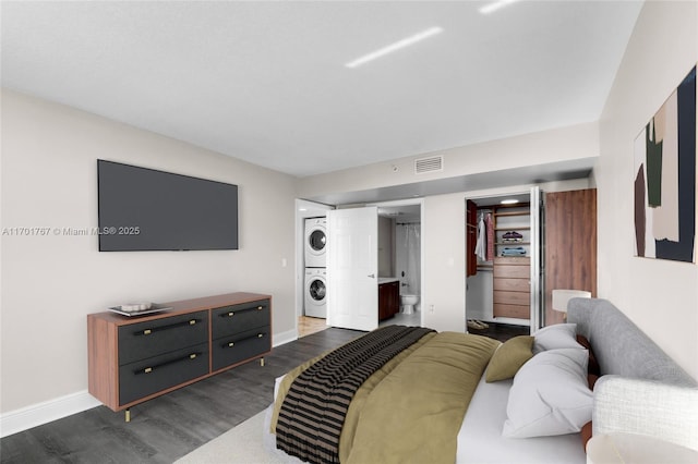 3000 Coral Way Unit 1502, Miami, FL 33145 - bedroom featuring estacked washer and dryer, dark wood-type flooring, baseboards, and ensuite bath