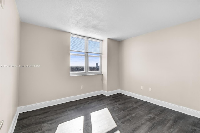 unfurnished room with dark hardwood / wood-style flooring and a textured ceiling