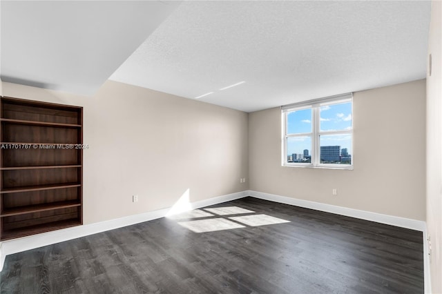 unfurnished room with a textured ceiling and dark wood-type flooring