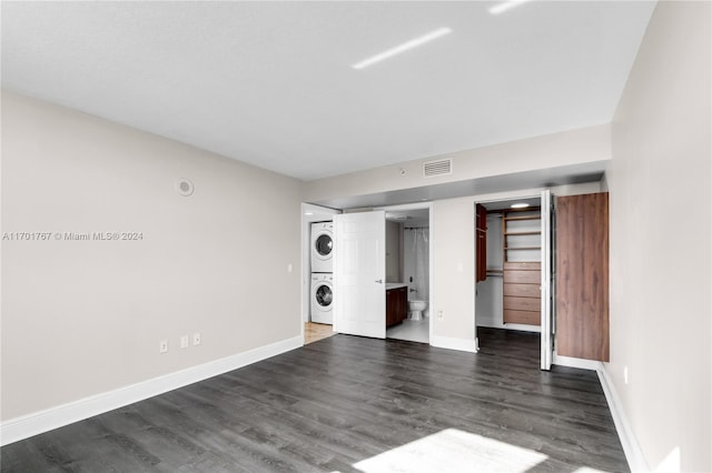 interior space with dark hardwood / wood-style flooring and stacked washing maching and dryer