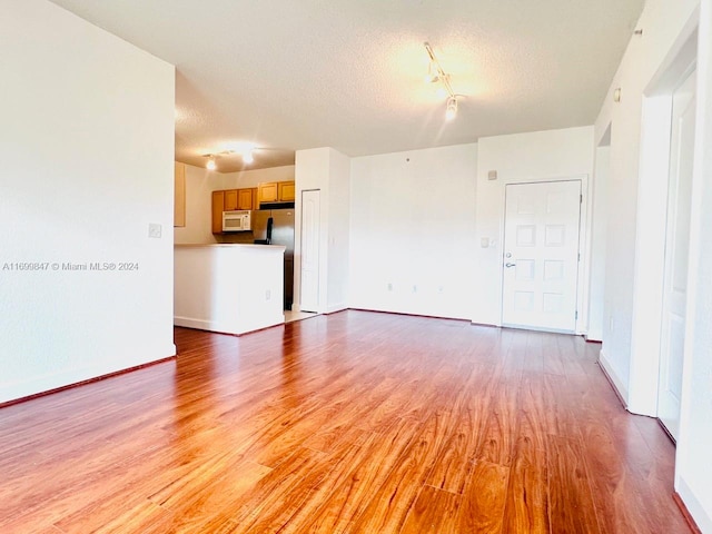 unfurnished living room featuring light wood-type flooring and a textured ceiling