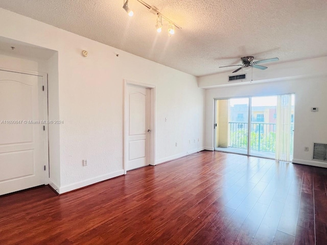 spare room featuring rail lighting, ceiling fan, dark hardwood / wood-style flooring, and a textured ceiling