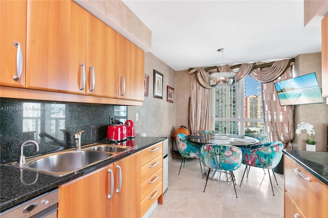 kitchen with backsplash, dark stone counters, sink, stainless steel dishwasher, and decorative light fixtures