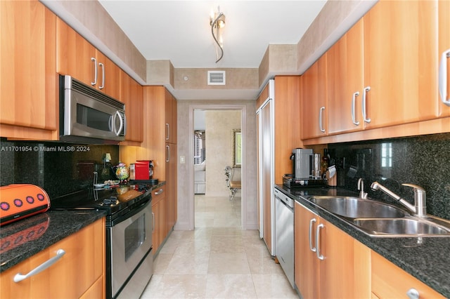 kitchen with backsplash, dark stone counters, sink, light tile patterned floors, and appliances with stainless steel finishes