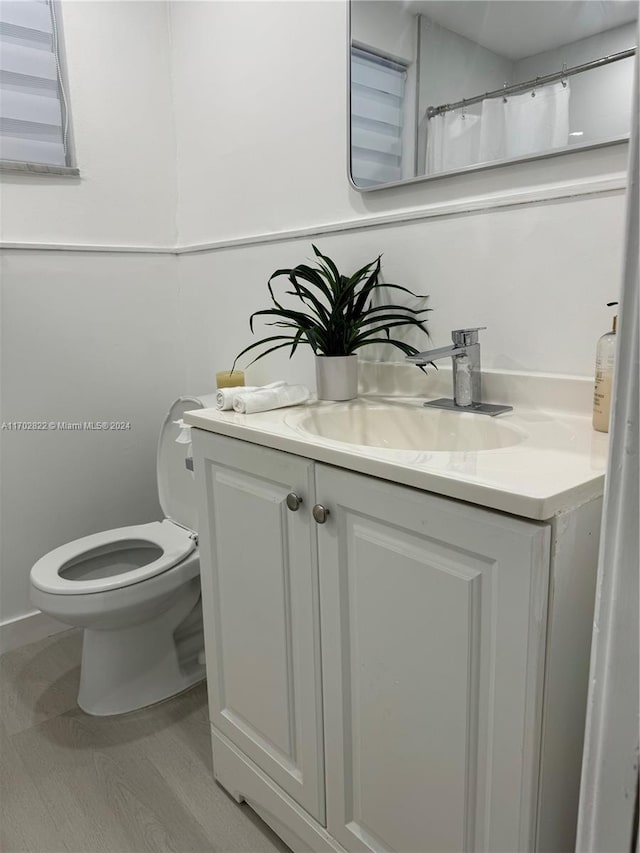 bathroom featuring toilet, vanity, and hardwood / wood-style flooring