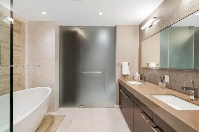 bathroom featuring tile patterned flooring, a bath, backsplash, vanity, and tile walls