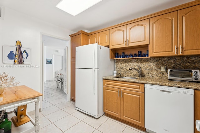 kitchen featuring sink, tasteful backsplash, dark stone countertops, white appliances, and light tile patterned floors