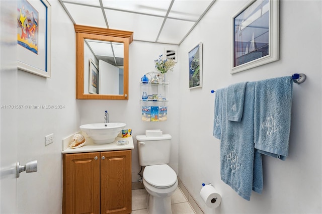 bathroom with tile patterned flooring, vanity, toilet, and a paneled ceiling