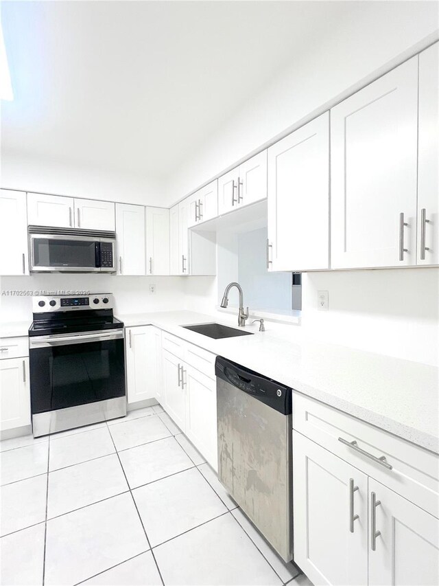 kitchen featuring white cabinetry, sink, light tile patterned floors, and stainless steel appliances