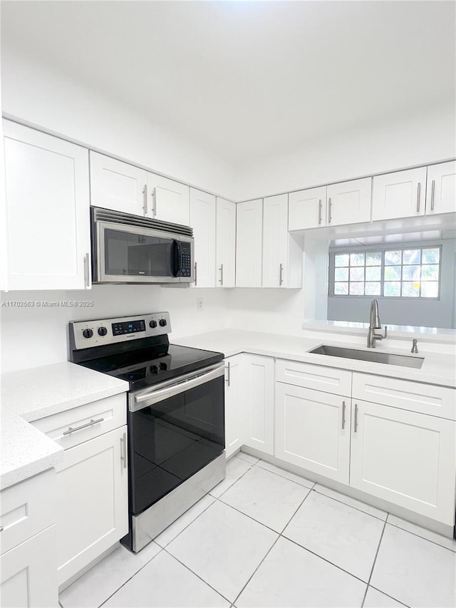 kitchen with white cabinetry, stainless steel appliances, sink, and light tile patterned floors