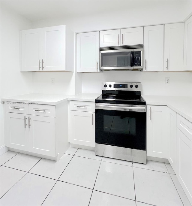 kitchen featuring appliances with stainless steel finishes, light tile patterned floors, and white cabinets