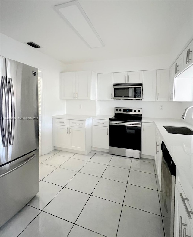 kitchen with white cabinetry, stainless steel appliances, sink, and light tile patterned floors