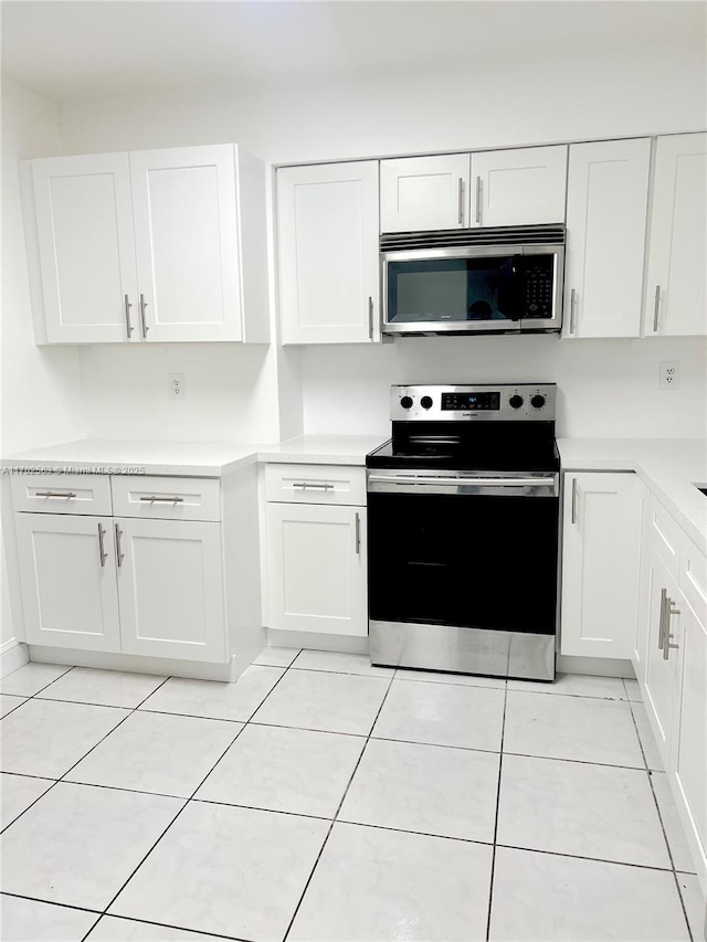 kitchen with stainless steel appliances, white cabinetry, and light tile patterned flooring