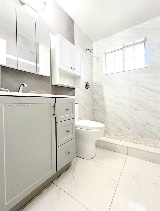 bathroom with vanity, tiled shower, and toilet