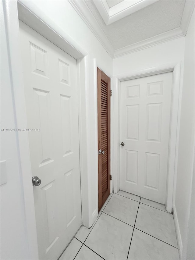 corridor featuring crown molding and light tile patterned flooring