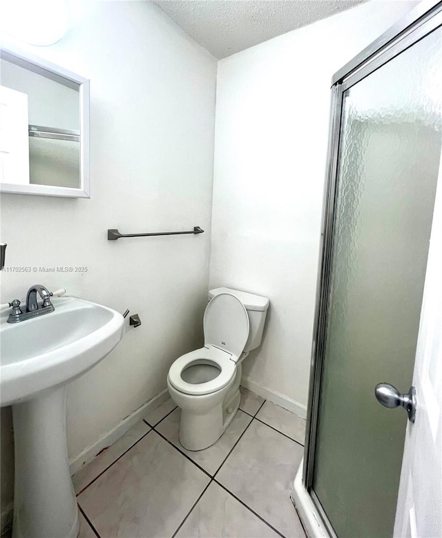 bathroom with sink, toilet, a shower with door, tile patterned floors, and a textured ceiling