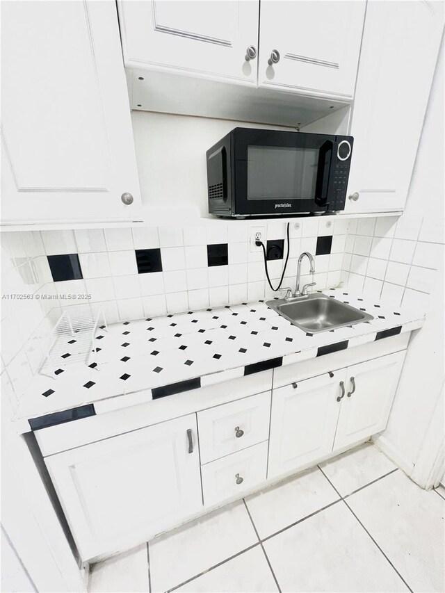 kitchen featuring white cabinetry, sink, light tile patterned floors, and decorative backsplash