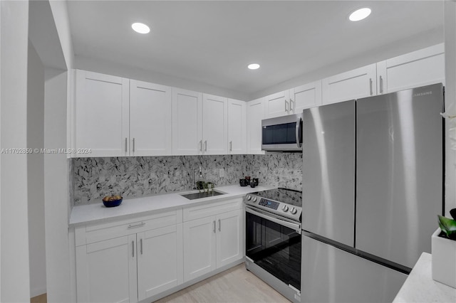 kitchen featuring white cabinets, backsplash, sink, and appliances with stainless steel finishes