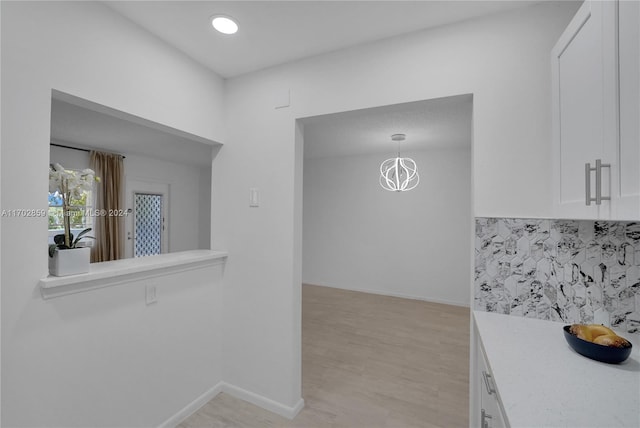 kitchen featuring white cabinetry, light hardwood / wood-style flooring, and decorative light fixtures