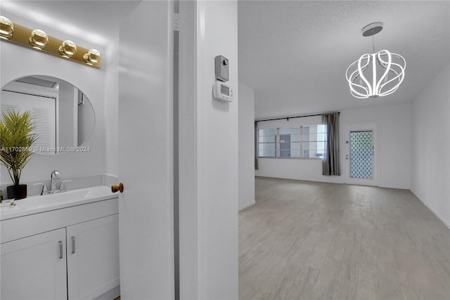 bathroom with an inviting chandelier, vanity, a textured ceiling, and hardwood / wood-style flooring