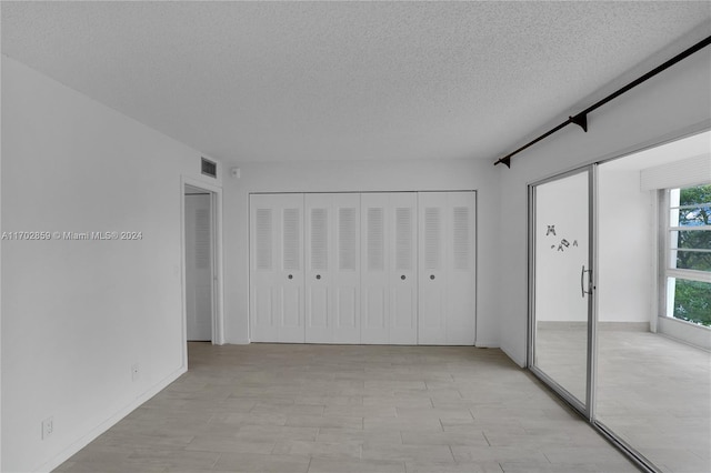 unfurnished bedroom featuring a textured ceiling and two closets