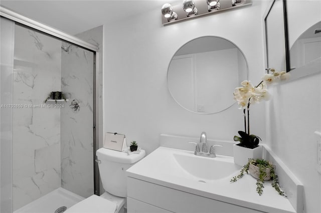 bathroom featuring a shower with door, vanity, and toilet