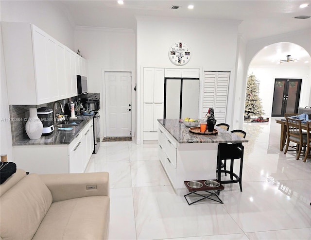 kitchen featuring white cabinets, a center island, and dark stone countertops