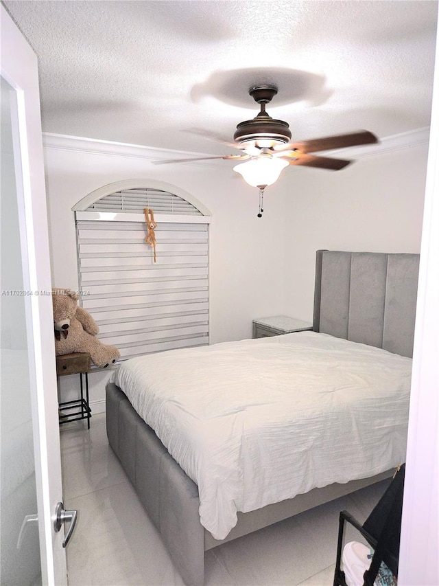 bedroom with ceiling fan and a textured ceiling