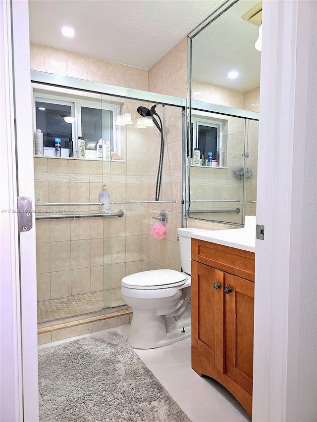 bathroom featuring tile patterned floors, vanity, toilet, and an enclosed shower