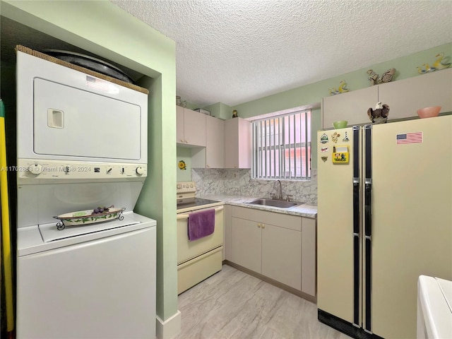 kitchen with sink, backsplash, stacked washer / dryer, a textured ceiling, and white appliances