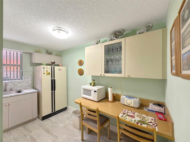 kitchen featuring a textured ceiling, white appliances, cream cabinets, and sink