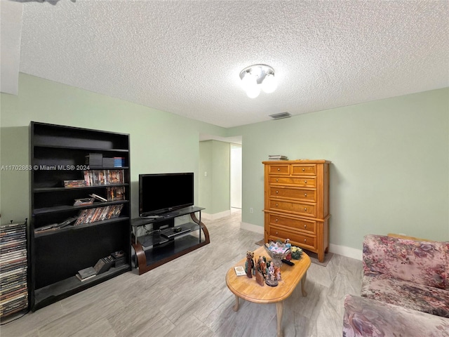 living room featuring a textured ceiling and light wood-type flooring