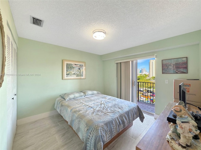 bedroom with a textured ceiling and access to outside