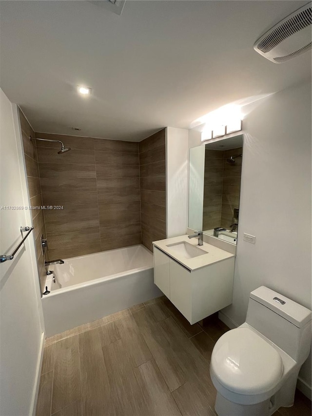 full bathroom featuring vanity, hardwood / wood-style flooring, toilet, and tiled shower / bath