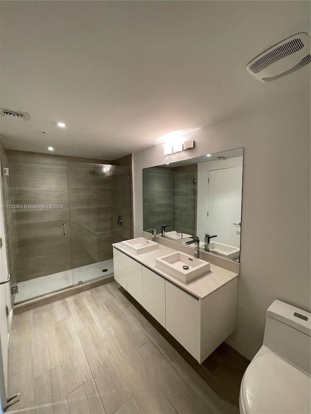 bathroom featuring hardwood / wood-style floors, vanity, toilet, and a shower with door