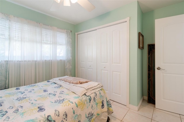 bedroom featuring ceiling fan, light tile patterned floors, and a closet