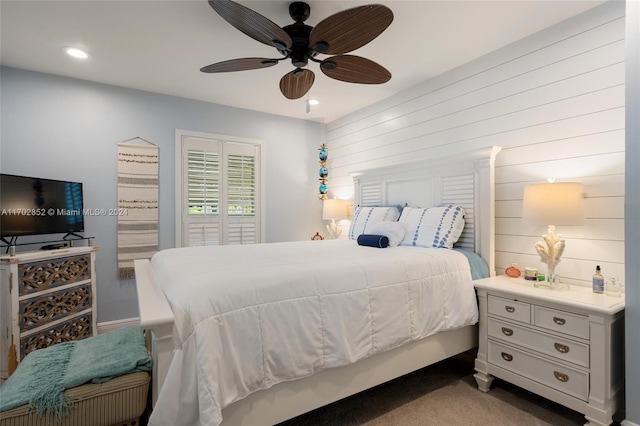 carpeted bedroom featuring ceiling fan and wooden walls