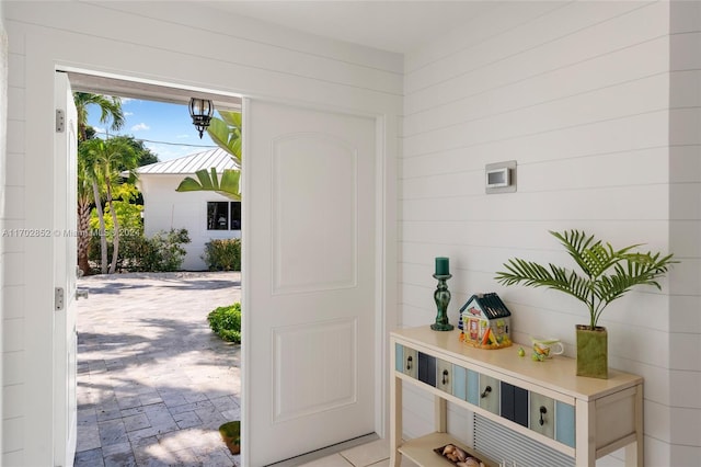 doorway to outside with wood walls