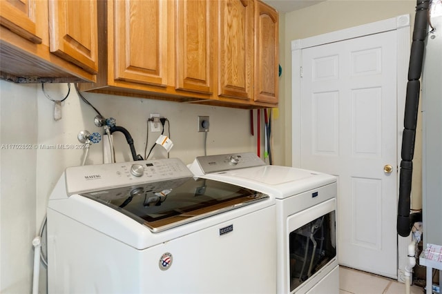 laundry area with washer and dryer, light tile patterned floors, and cabinets