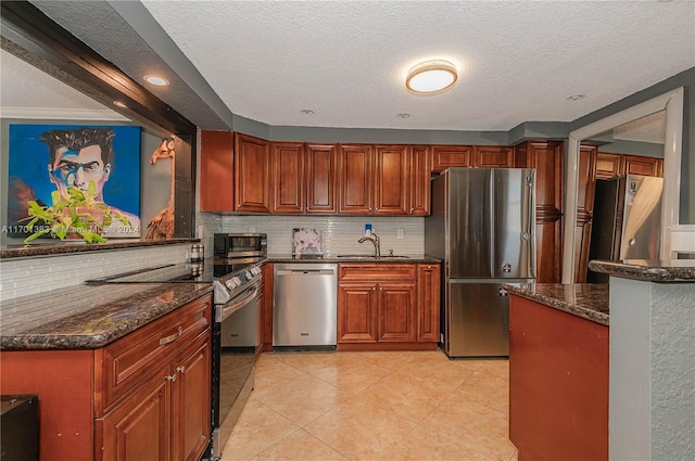 kitchen with dark stone countertops, sink, a textured ceiling, and appliances with stainless steel finishes