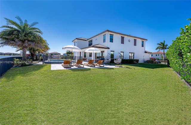 rear view of property featuring a lawn, a fenced in pool, and a patio