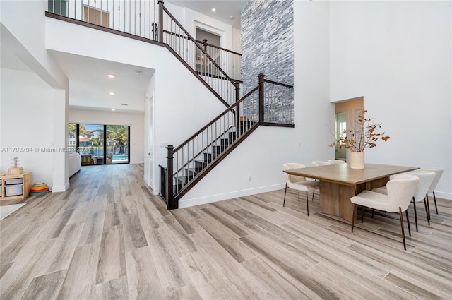 dining space featuring light hardwood / wood-style floors and a high ceiling