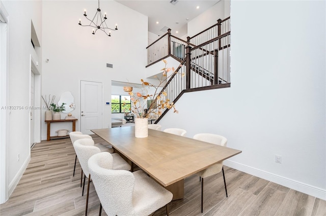 dining area with a high ceiling, light wood-type flooring, and a notable chandelier