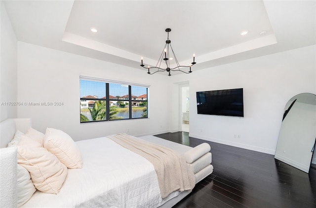 bedroom featuring a notable chandelier, a raised ceiling, and dark wood-type flooring