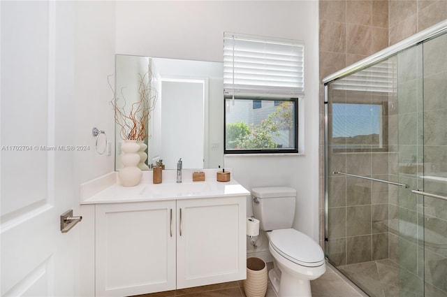 bathroom featuring tile patterned floors, vanity, toilet, and walk in shower