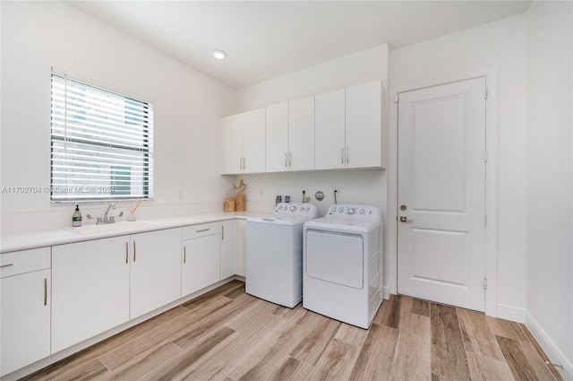 washroom with cabinets, independent washer and dryer, sink, and light hardwood / wood-style flooring