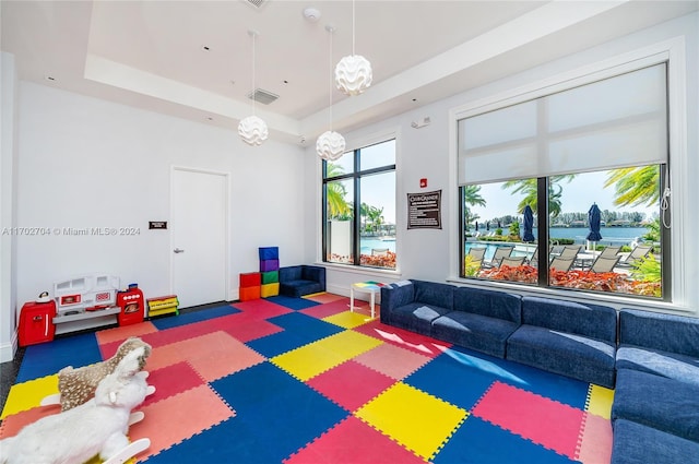 playroom featuring a tray ceiling and dark colored carpet