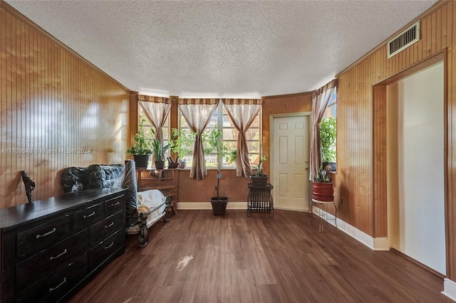 sitting room featuring a textured ceiling, wood walls, and dark hardwood / wood-style floors